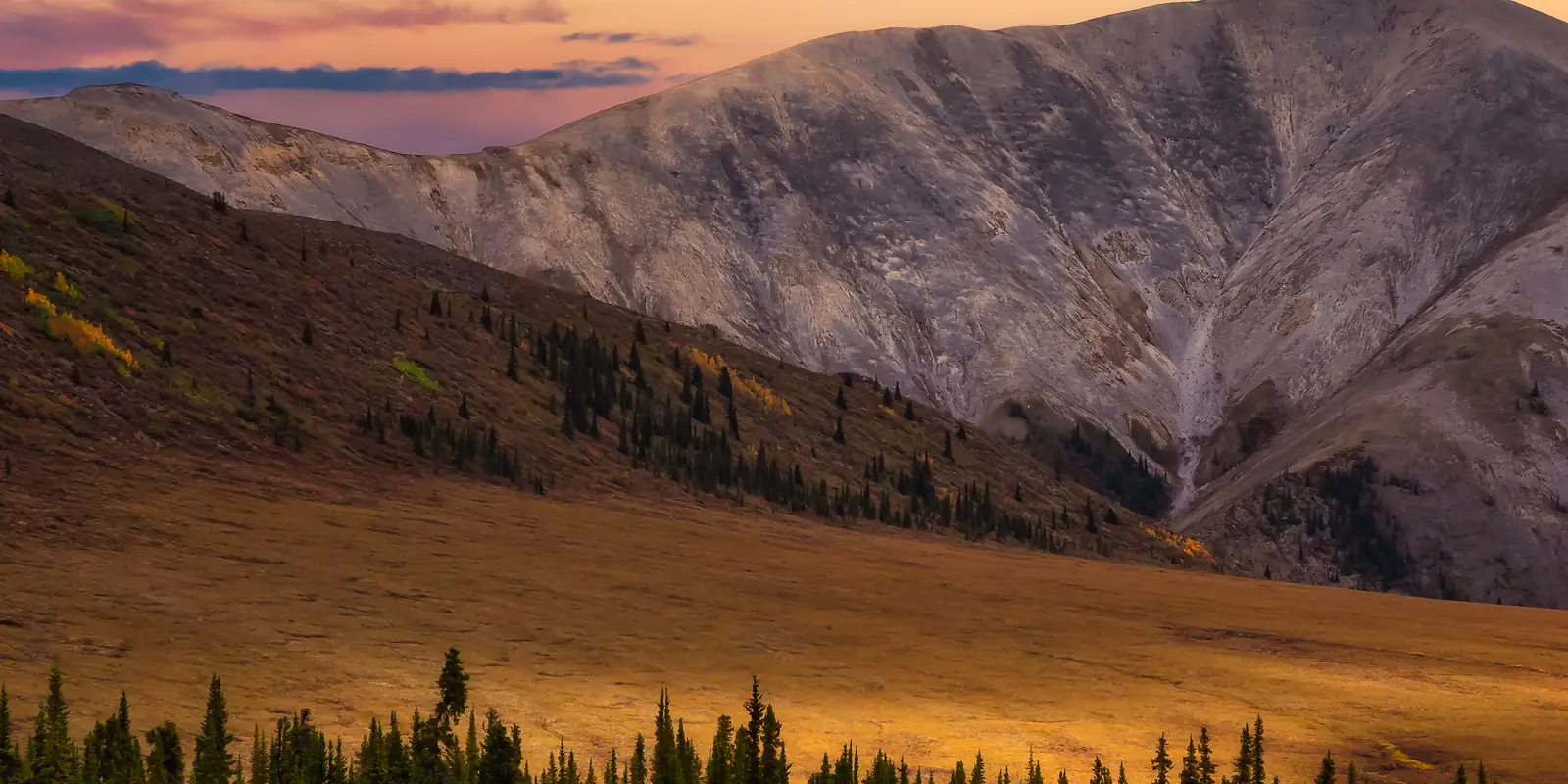 Autumn forest and mountains under a fiery sunset sky